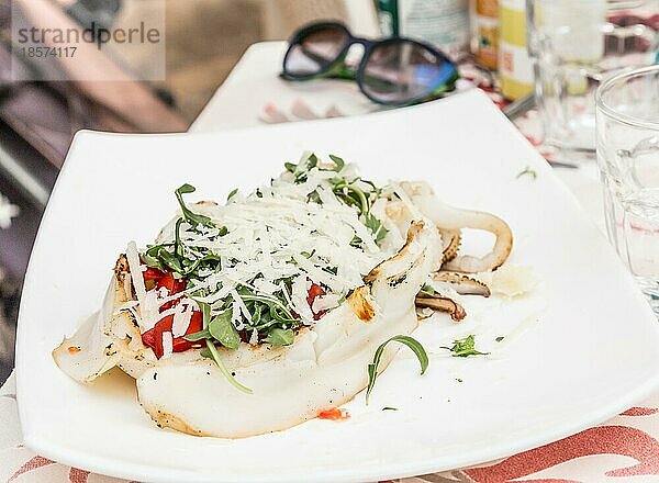 Italienisches Restaurant in Gallipoli  Region Apulien (Süditalien) . Traditioneller Tintenfisch mit frischem Salat  Tomaten und echtem Parmigiano Käse. Tageslicht