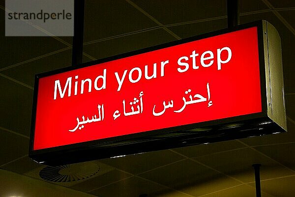 Vorsicht Schild in einem internationalen Flughafen im Nahen Osten mit arabischen Informationen