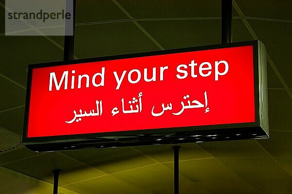 Vorsicht Schild in einem internationalen Flughafen im Nahen Osten mit arabischen Informationen