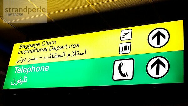 Gepäckausgabe und Telefonschild in einem internationalen Flughafen im Nahen Osten mit arabischen Informationen