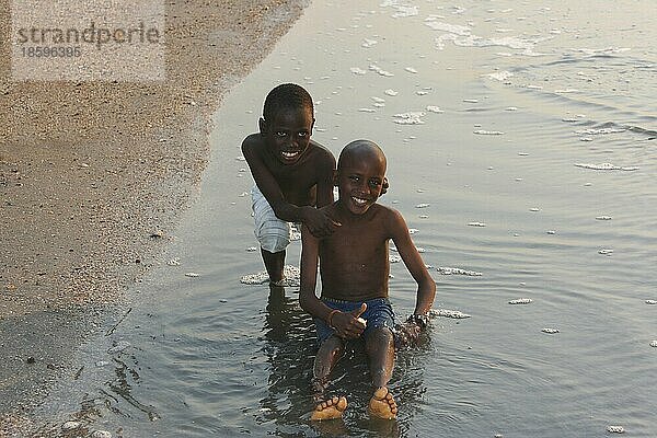 Zwei Jungs siten im Wasser am Strand von Bakau  Gambia  Afrika