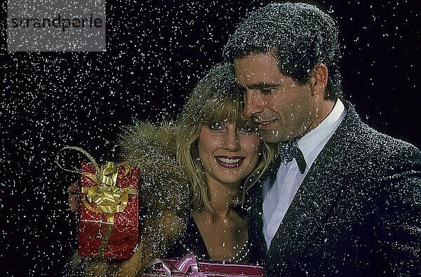 Liebespaar mit Weihnachtsgeschenk  Schneeflocken auf der Schulter  Schneetreiben
