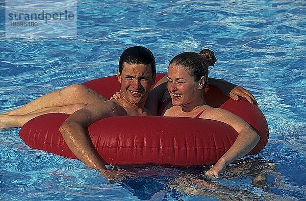 Junges Paar tobt mit roter Schwimmreifen im swimmingpool