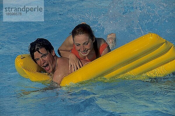 Junges Paar tobt mit gelber Luftmatratze im swimmingpool