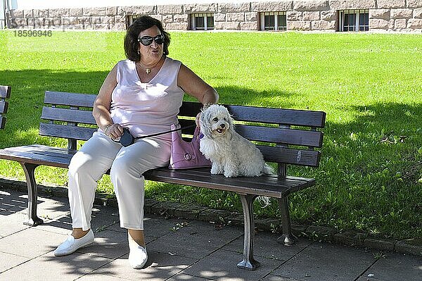 Ältere Frau mit Hund auf Parkbank