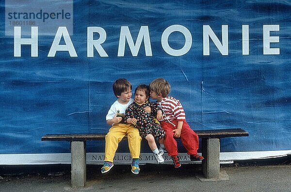 Little children on bench in front of advertisement  /  Bavaria  Germany  Kleine Kinder auf Bank vor Werbeplakat mit Aufschrift Harmonie  Bayern  Deutschland  Europa