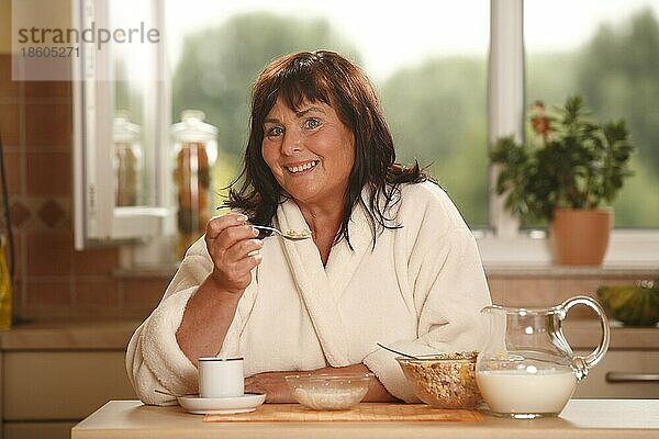 Frau beim Frühstück  Frühstück  frühstücken  Kanne Milch  Schüsseln  Müsli  Tasse Kaffee  frühstückt  Löffel