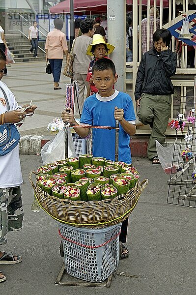 Boy selling roses wrapped in banana leaves  Chatuchak Market  Bangkok  Thailand  Junge verkauft Rosen eingewickelt in Bananenblätter  Chatuchak-Markt  Bangkok  Thailand  Asien