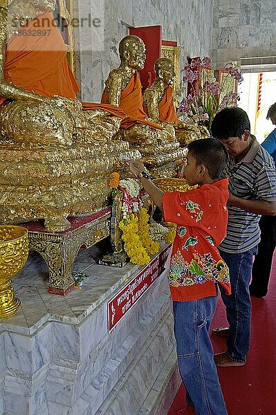 Thai boy adhering golden plate on statue in Wat Chalong Temple  Phuket  Thailand  Thai-Junge klebt Goldplättchen auf Statue im Wat Chalong Tempel  Phuket  Thailand  Asien