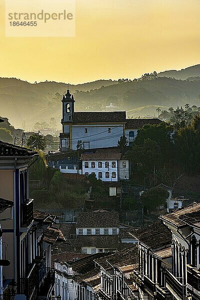 Alte Kirche in der Stadt Ouro Preto bei Sonnenuntergang mit Häusern im Kolonialstil  Dächern und den Bergen im Hintergrund  Brasilien  Südamerika