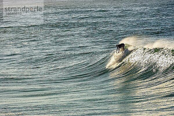 Silhouette eines Surfers am Strand von Ipanema  Rio de Janeiro während der Sommerdämmerung  Strand von Ipanema  Rio de Janeiro  Rio de Janeiro  Brasilien  Südamerika