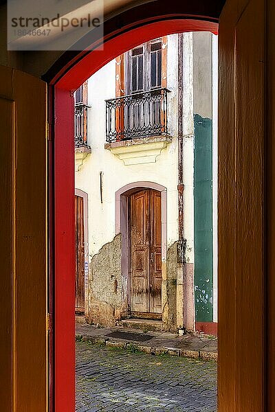 Alte Tür in kolonialer Architektur  die sich im Laufe der Zeit verschlechtert hat  gesehen durch eine andere Tür  die ebenfalls alt ist und die gleiche Architektur aufweist  in der Stadt Ouro Preto  Ouro Preto  Minas Gerais  Brasilien  Südamerika