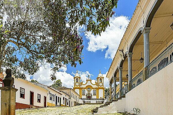 Eine ruhige historische Kopfsteinpflasterstraße in der Stadt Tiradentes in Minas Gerais mit Kolonialhäusern und einer Barockkirche im Hintergrund  Brasilien  Südamerika
