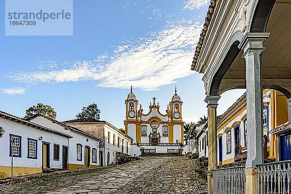 Eine ruhige historische Straße in der Stadt Tiradentes in Minas Gerais mit Kolonialhäusern und einer Barockkirche im Hintergrund  Brasilien  Südamerika