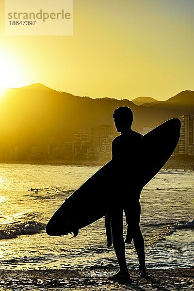 Surfer Silhouette mit seinem Longboard mit Blick auf die Iapnema Strand Wellen in Rio de Janeiro während des Sonnenuntergangs  Brasilien  Südamerika