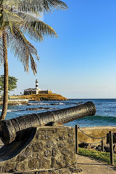 Alte Kanone aus der Zeit des Kaiserreichs  die zur Verteidigung der Stadt Salvador in Bahia eingesetzt wurde  mit Farol da Barra und dem Meer im Hintergrund  Brasilien  Südamerika