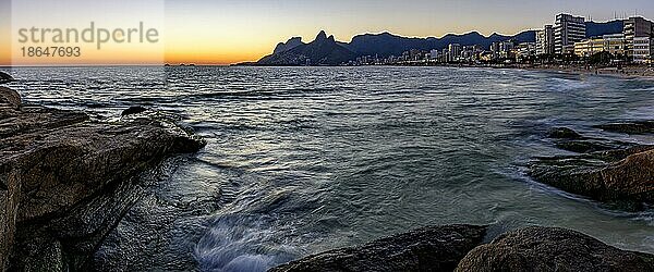 Panoramabild des Sonnenuntergangs am Strand von Ipanema in Rio de Janeiro mit dem Meer  Gebäuden und Bergen  die für die Stadt charakteristisch sind  Brasilien  Südamerika