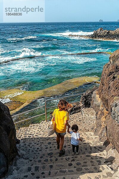 Eine Mutter mit ihrem Sohn beim Abstieg in das Felsbecken La Maceta auf der Insel El Hierro auf den Kanarischen Inseln