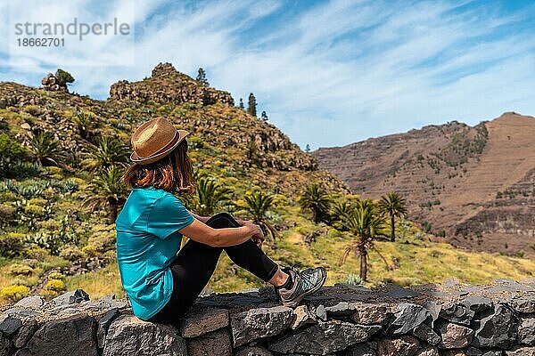 Ein junger Tourist genießt die Aussicht am Aussichtspunkt von El Palmarejo auf La Gomera  Kanarische Inseln