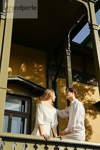 Junges verliebtes Paar  das auf einem Balkon steht und sich gegenseitig anschaut