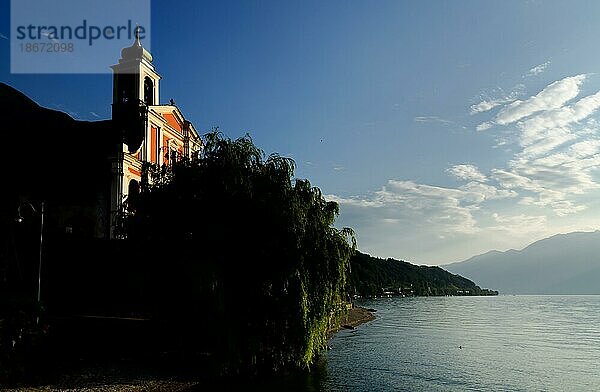 Kirche mit Sonnenlicht am Lago Maggiore mit Berg und blauem Himmel im Tessin  Schweiz  Europa