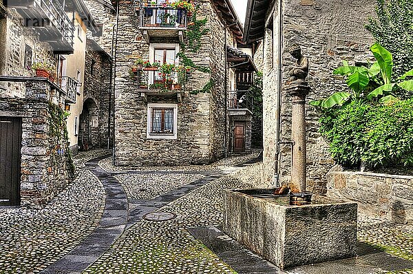 Rustikales Dorf mit einem Brunnen aus Stein in Arcegno  Schweiz  Europa