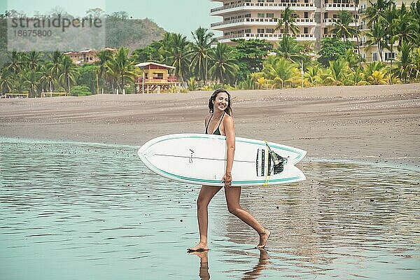 Schöne junge Latina mit Surfbrett am Ufer zu Fuß in Richtung Meer. Urlaub und Sommer Konzept. Konzept des gesunden und aktiven Lebens