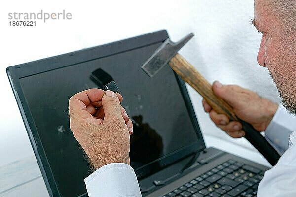 Wütender Mann im Profil  der einen Laptop mit einem Hammer zerschlägt  weißer Hintergrund und Kopierraum