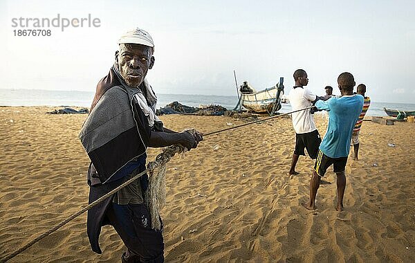 Alter Fischer hilft einen Fang an Land zu ziehen  Togo  Lome.  Lome  Togo  Afrika