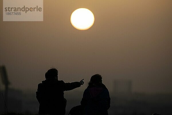Zwei Personen zeichnen sich vor der aufgehenden Sonne ab in Berlin  25.02.2021. Copyright: Berlin  Deutschland  Europa