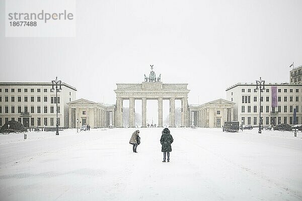 Berlin  Zwei Personen  aufgenommen auf dem Pariser Platz vor dem Brandenburger Tor nach während starken Schneefalls in Berlin