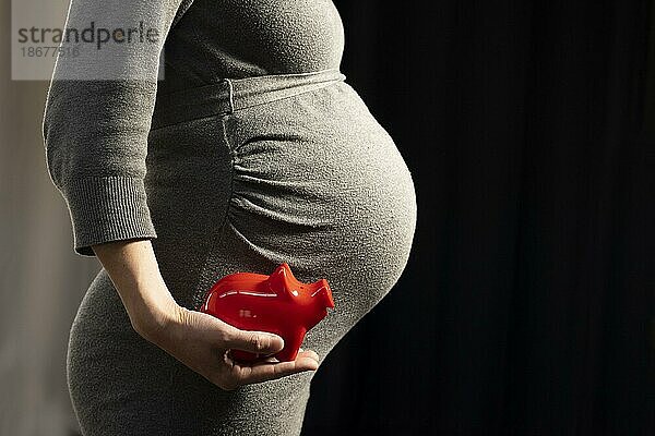 Schwangere Frau mit Sparschwein. Kosten für ein Kind  Bonn  Deutschland  Europa