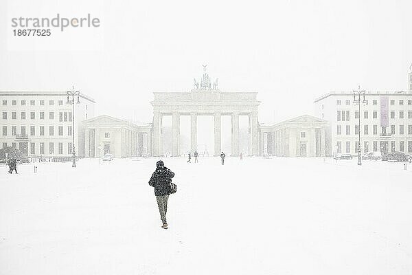 Berlin  Eine einzelne Person  aufgenommen auf dem Pariser Platz vor dem Brandenburger Tor nach während starken Schneefalls in Berlin