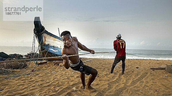 Junger Fischer hilft einen Fang an Land zu ziehen  Togo  Lome.  Lome  Togo  Afrika