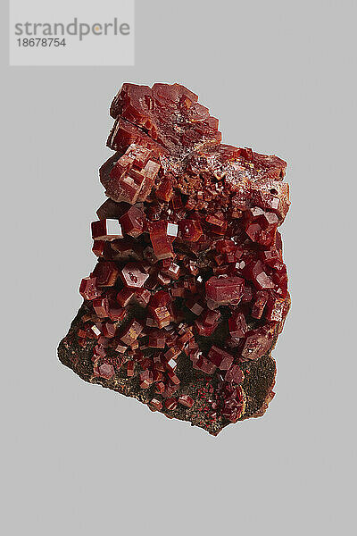 Nahaufnahme eines strukturierten roten marokkanischen Vanadinit-Kristalls auf grauem Hintergrund