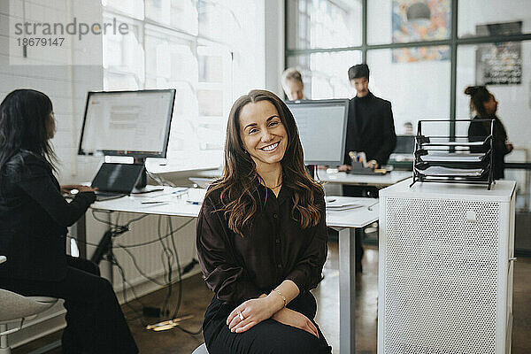 Porträt einer lächelnden Geschäftsfrau  die im Büro eines Unternehmens sitzt