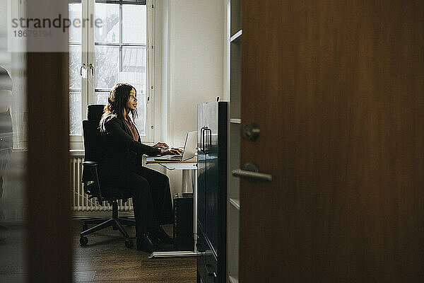 Unternehmerin sitzt auf einem Stuhl und arbeitet im Büro