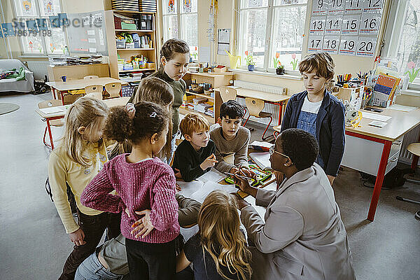 Lehrerin  die Jungen und Mädchen im Klassenzimmer der Grundschule betreut