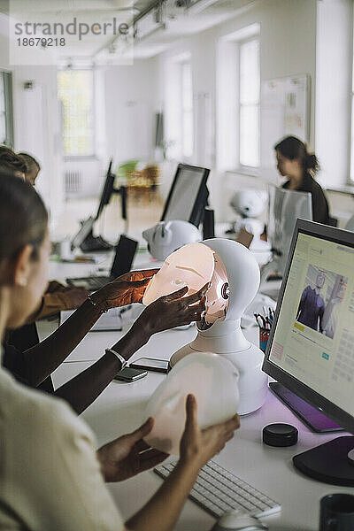 Multirassische Studenten diskutieren über soziale Roboter am Schreibtisch im Innovationslabor
