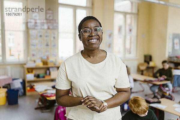 Porträt einer glücklichen Lehrerin mit Brille im Klassenzimmer