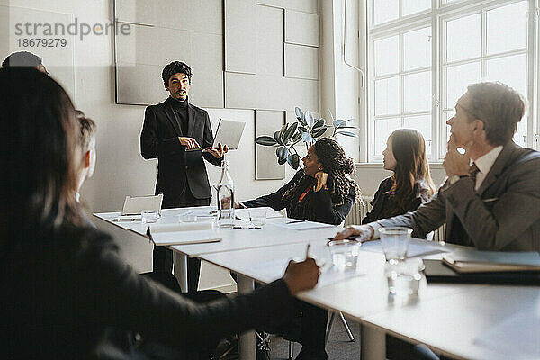 Männlicher Unternehmer  der eine Geschäftsbesprechung mit seinem Team im Sitzungssaal seines Büros abhält
