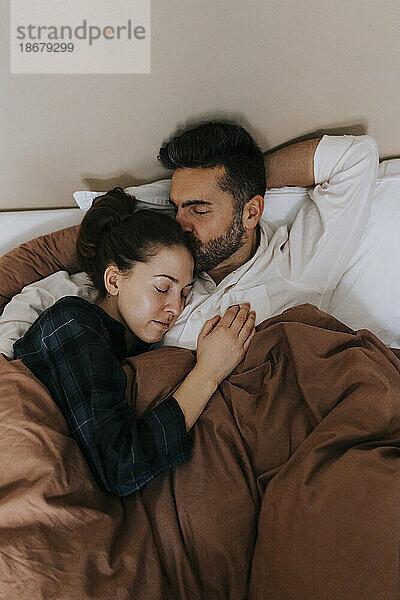 Hohe Winkel Ansicht des Mannes küssen nicht-binäre Person im Bett zu Hause entspannen