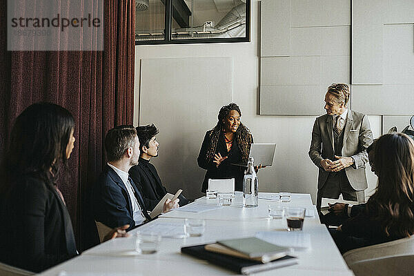 Unternehmerin im Gespräch mit männlichen und weiblichen Kollegen während eines Geschäftstreffens im Büro