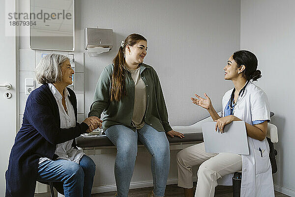 Ärztin erklärt Patientin  die mit ihrer Mutter in der Klinik sitzt