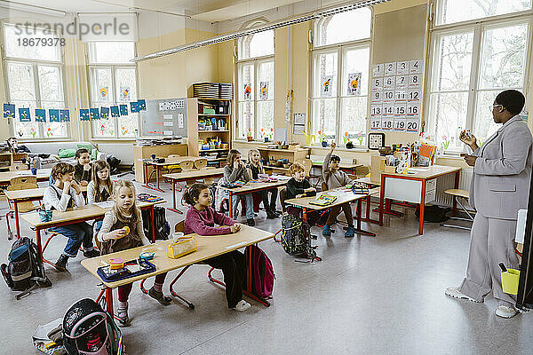 Lehrerin mit Jungen und Mädchen im Klassenzimmer in der Schule