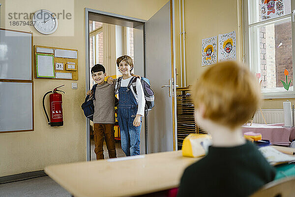 Glückliche Schüler  die sich in den Armen liegen  wenn sie das Klassenzimmer betreten und einen Freund ansehen