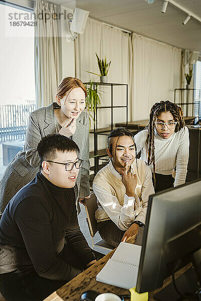 Männliche und weibliche Programmierer diskutieren über Computer am Schreibtisch in einem kreativen Büro