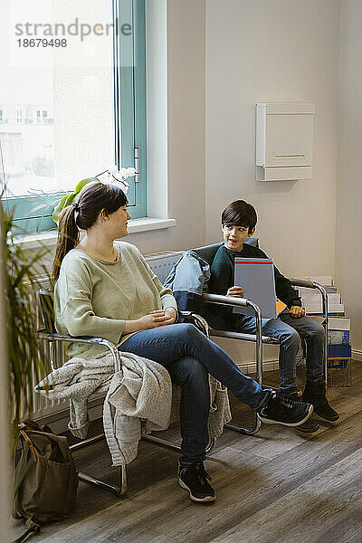 Mutter und Tochter sitzen auf einem Stuhl im Wartezimmer einer Klinik