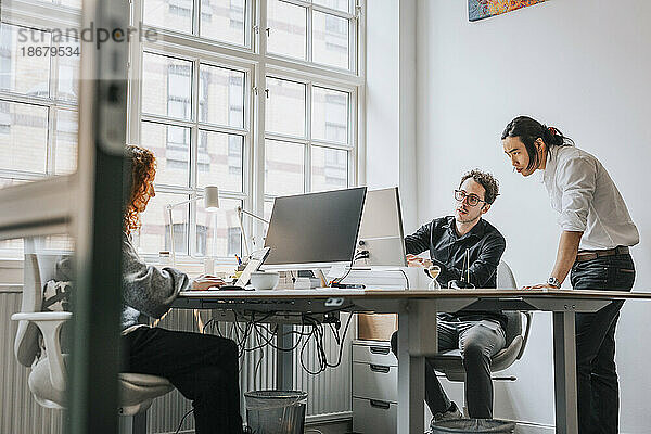Geschäftsleute diskutieren über Desktop-PC am Schreibtisch im Büro