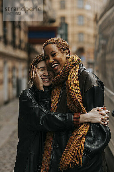 Glückliches nicht-binäres Paar  das sich umarmt  während es auf der Straße steht